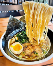 Bowl of ramen with noodles lifted by chopsticks